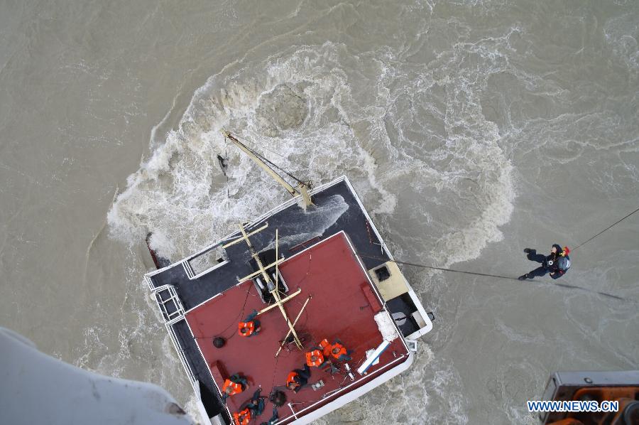 A rescuer hangs from a helicopter to help seamen on a wrecked freighter at the sea near Basuo Port in Dongfang, southernmost China's Hainan Province, June 23, 2013. Feignters "Changxinshun 888" and "Jinma 788" capsized due to the arrival of tropical storm Bebinca near Basuo Port Sunday. All the 12 crew members were saved by local maritime safety administration and the First Rescue Squadron of the South China Sea. (Xinhua) 