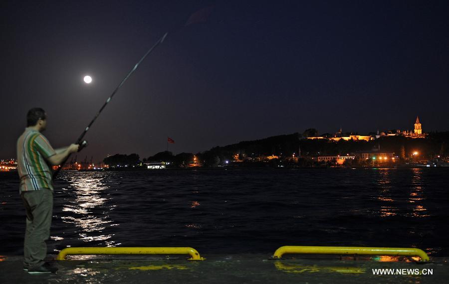 A man fishes under a super moon in Istanbul on June 23, 2013. On Sunday a perigee moon coincided with a full moon creating a "super moon" when it passed by the earth at its closest point in 2013. (Xinhua/Lu Zhe)