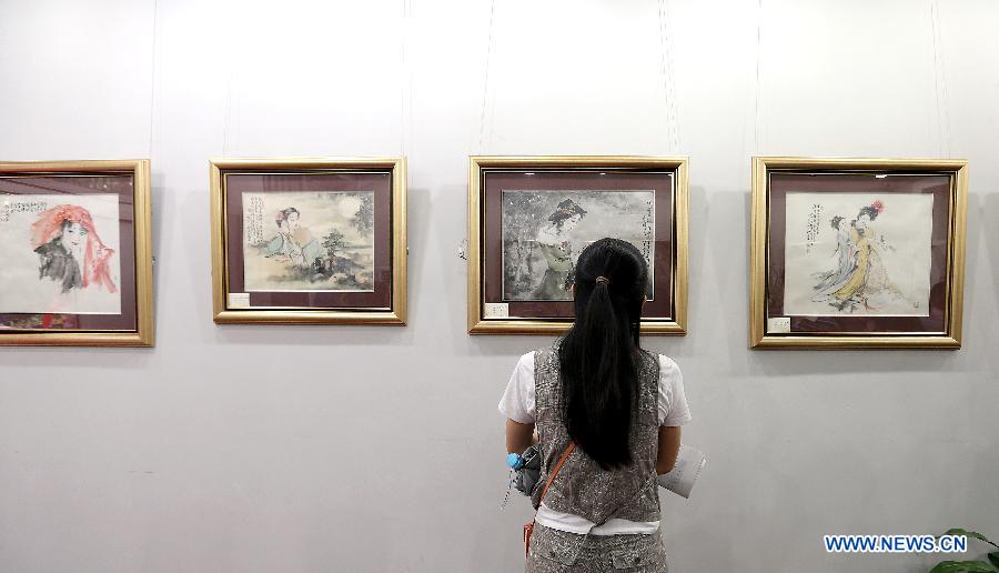 A visitor watches an exhibited painting at a gallery in Beijing, capital of China, June 22, 2013. A total of 40 paintings and calligraphic works created by artist Bai Bohua were exhibited on a gallery show here on June 22. (Xinhua/Zhang Chuanqi)