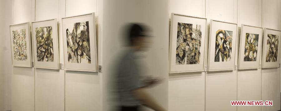 A visitor walks past the exhibited paintings on a gallery show in Hong Kong, south China, June, 24, 2013. A gallery show exhibition of the paintings created by artist Xiao Jiahong opened here on Monday. (Xinhua/Lui Siu Wai)