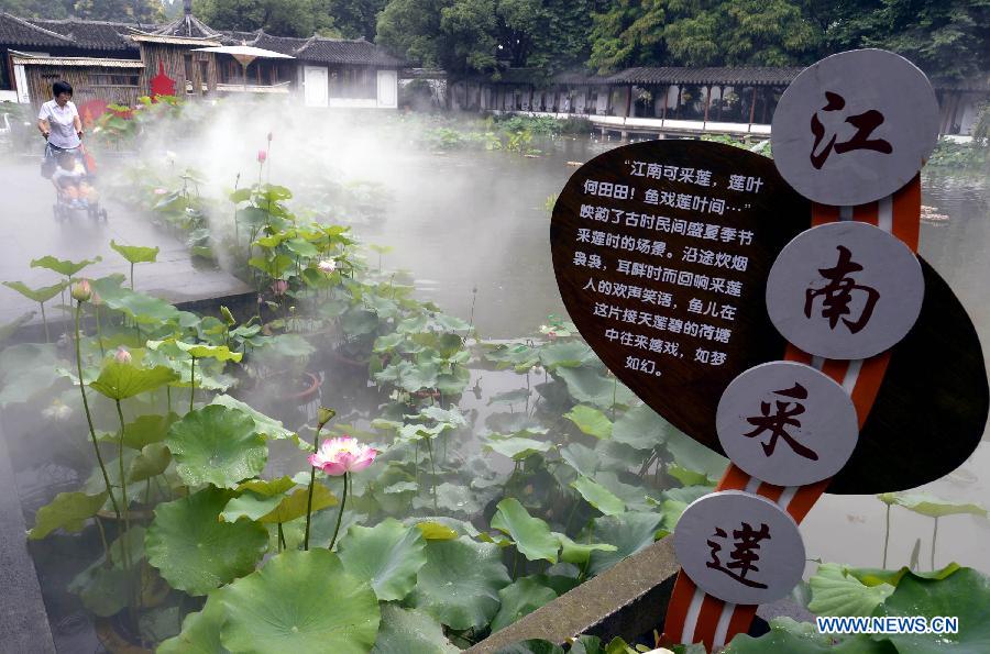 Visitors look at lotus flowers during an art festival along the West Lake in Hangzhou, capital of east China's Zhejiang Province, June 24, 2013. The festival will last till July 31. (Xinhua/Shi Jianxue) 