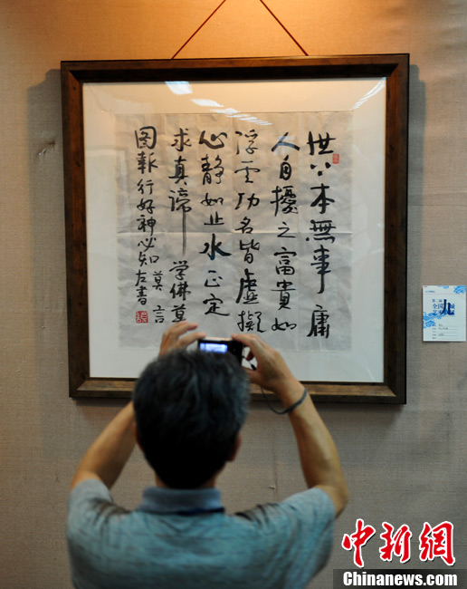 On June 23, 2013, a visitor watches Mo Yan's calligraphic work "No Troubles at First". At an art show held in Jinan, east China's Shandong province, two calligraphic works of Chinese writer and the Nobel Prize winner Mo Yan - "King of Sweden" and "No Trouble at First" - were priced 500,000 yuan and 200,000 yuan respectively. The art show has attracted many fans of Mo Yan. (CNS/Zhang Yong)