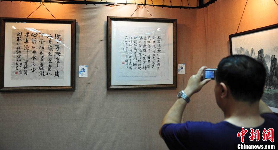 On June 23, 2013, a Mo Yan's fan takes photos of his calligraphic works. At an art show held in Jinan, east China's Shandong province, two calligraphic works of Chinese writer and the Nobel Prize winner Mo Yan - "King of Sweden" and "No Trouble at First" - were priced 500,000 yuan and 200,000 yuan respectively. The art show has attracted many fans of Mo Yan. (CNS/Zhang Yong)