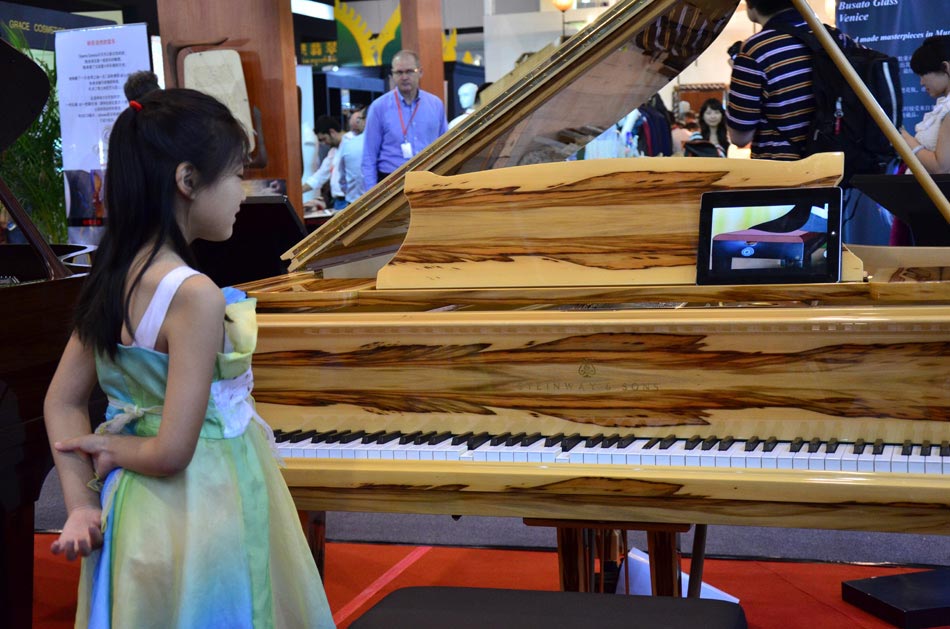 A girl watches an automatic piano at the Luxury China 2013 exhibition in Beijing on June 22, 2013. The 3-day exhibition closed on June 24 at the China International Exhibition Center in Beijing. [Wang Yu / chinadaily.com.cn ]