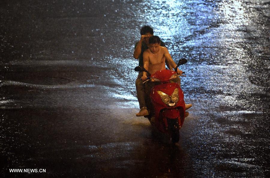 People ride in the rain on a street in Beijing, capital of China, June 24, 2013. Thunder storm visited the capital city on Monday night. (Xinhua/Wang Qingqin) 