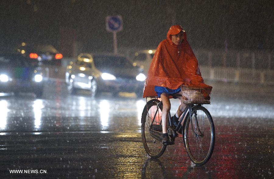 A man rides in the rain on a street in Beijing, capital of China, June 24, 2013. Thunder storm visited the capital city on Monday night. (Xinhua/Wang Qingqin)
