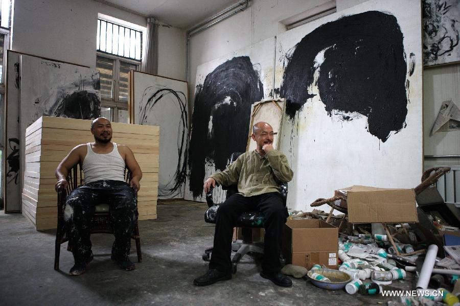 Zhang Fangbai (R), a 51-year-old painter, talks with Wu Zhenhuan, head of the Beijing Museum of Contemporary Art, at Zhang's studio in Beijing, capital of China, June 20, 2013. Zhang has specialized in painting eagles for a dozen of years. (Xinhua/Wu Xiaochu)