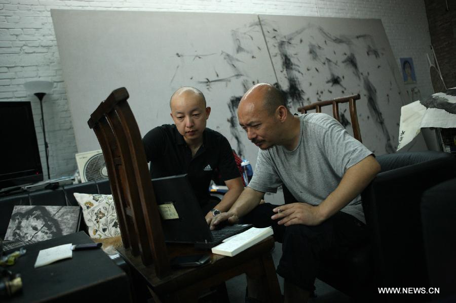 Zhang Fangbai (R), a 51-year-old painter, and his assistant check information in computer at Zhang's studio in Beijing, capital of China, June 19, 2013. Zhang has specialized in painting eagles for a dozen of years. (Xinhua/Wu Xiaochu) 