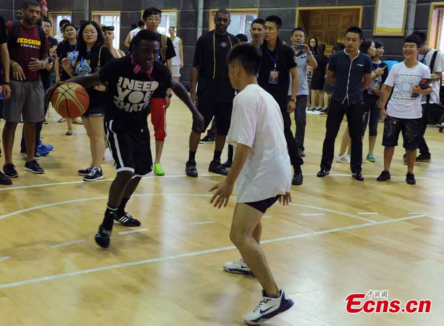 An NBA star plays with a Chinese basketball player on a basketball court at the Jin Qiang national basketball training base in Chengdu, Southwest China's Sichuan Province, June 24, 2013. NBA stars visited Chengdu on Monday and played a game against with China's August 1 Men's Basketball Team. (CNS/Liu Zhongjun)