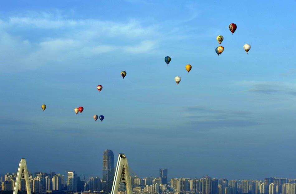 Hot-air balloons fly over the city zone during the 7th Hot Air Balloon Festival and 2013 H1 China Hot Air Balloon Challenge in Haikou, capital of south China's Hainan province, June 18, 2013. A total of 15 hot-air balloons took part in the event Tuesday to fly across the Qiongzhou Strait from the city of Haikou and reached a designated place in neighboring Guangdong province. (Photo by Jiang Jurong/ Xinhua)