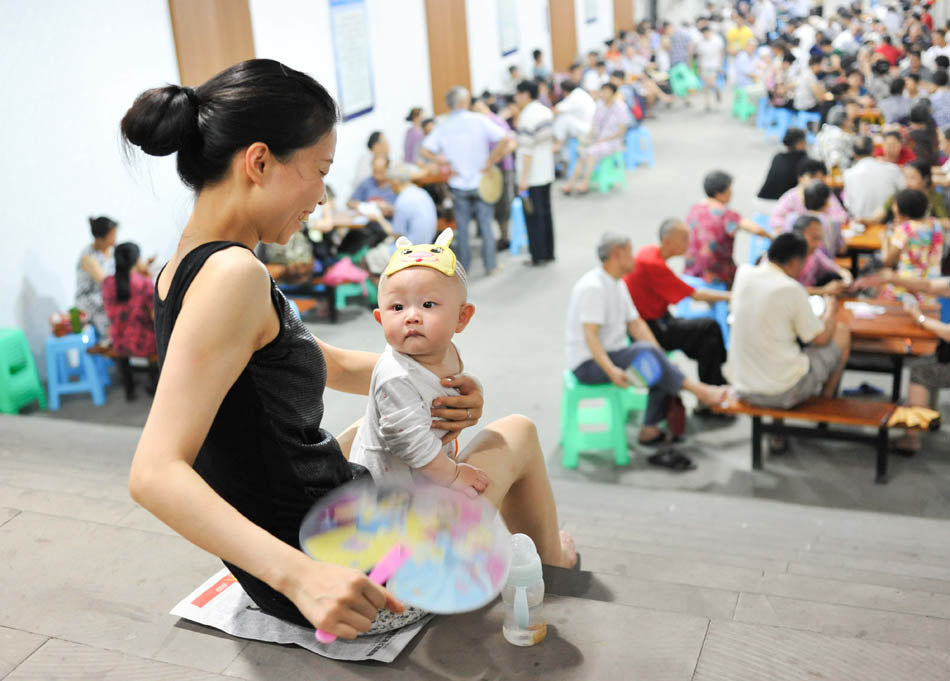A woman holds her baby in arms in a public shelter where citizens enjoy the cool air in Chongqing. The city’s meteorological bureau issued a high temperature orange warning signal since temperature sustained over 39 degrees Celsius in some regions. (Photo by Liu Chan/ Xinhua)