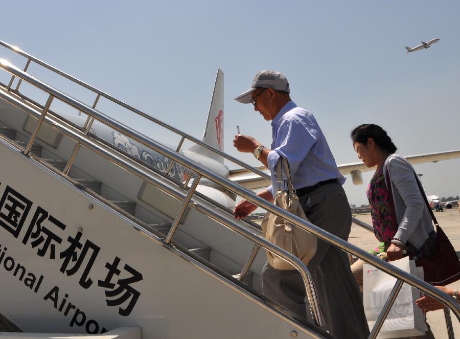 Passengers board an airplane to leave for Taipei, southeast China's Taiwan, in Hohhot, capital of north China's Inner Mongolia Autonomous Region, June 25, 2013. Air China opened the direct flight from Hohhot to Taipei on Tuesday. (Xinhua/Yu Jia)