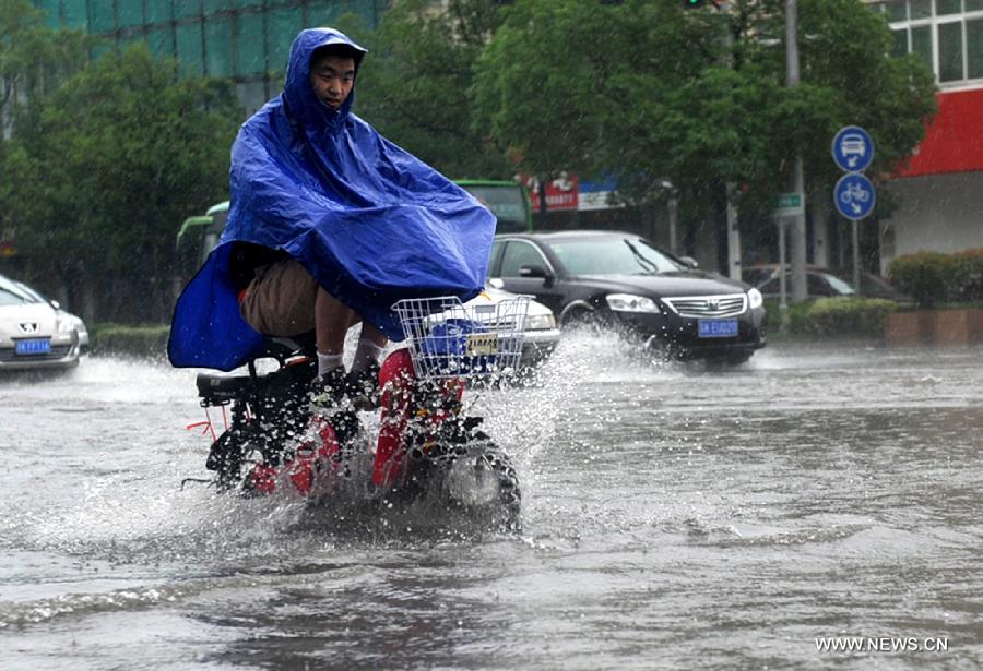 A citizen rides on the waterlogged road in Yangzhou City, east China's Jiangsu Province, June 25, 2013. Heavy rainfall hit many parts of Jiangsu on Tuesday. (Xinhua)