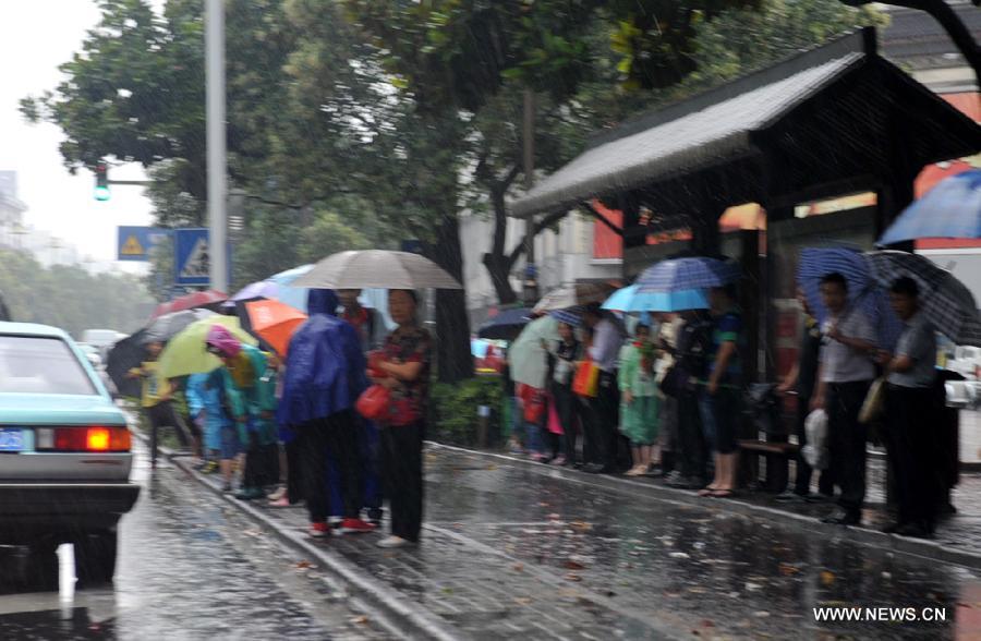 Citizens wait for buses on the waterlogged road in Yangzhou City, east China's Jiangsu Province, June 25, 2013. Heavy rainfall hit many parts of Jiangsu on Tuesday. (Xinhua)