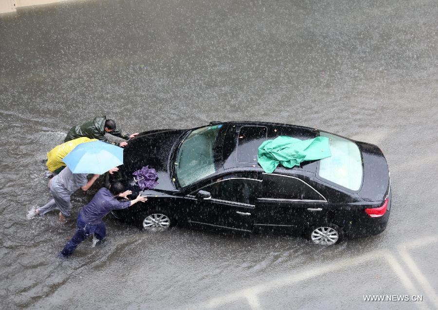 Citizens push a car on a waterlogged road in Nanjing City, capital of east China's Jiangsu Province, June 25, 2013. Heavy rainfall hit many parts of Jiangsu on Tuesday. (Xinhua)