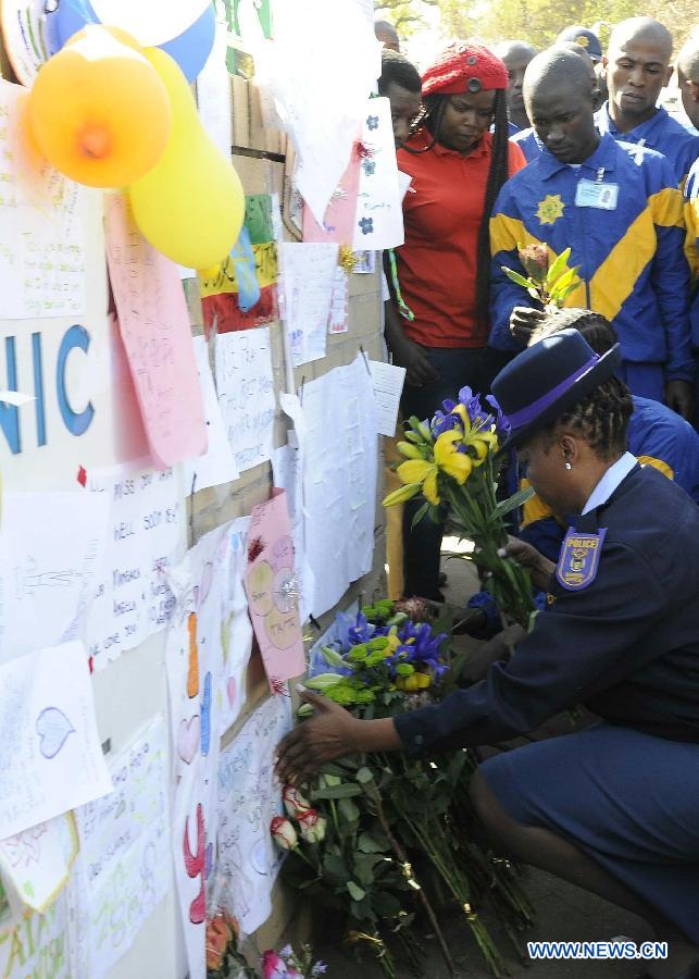 Police officers present flowers to former South African president Nelson Mandela outside the hospital where Mandela is treated in Pretoria, South Africa, on June 25, 2013. South Africans on Monday were holding their breath over former President Nelson Mandela's health that has deteriorated from serious to critical. Mandela, 94, has been hospitalized for a recurring lung problem since June 8. (Xinhua/Li Qihua)