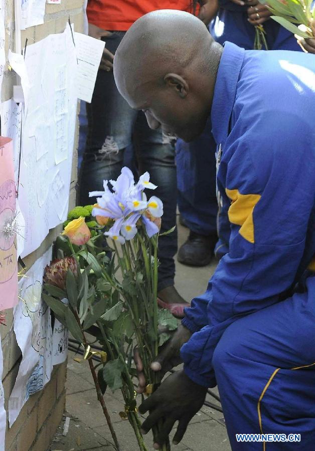 A Police officer presents flowers to former South African president Nelson Mandela outside the hospital where Mandela is treated in Pretoria, South Africa, on June 25, 2013. South Africans on Monday were holding their breath over former President Nelson Mandela's health that has deteriorated from serious to critical. Mandela, 94, has been hospitalized for a recurring lung problem since June 8. (Xinhua/Li Qihua)
