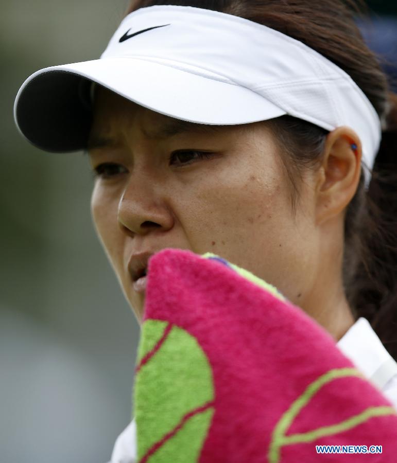 Li Na of China wipes her face with a towel during the first round of ladies' singles against Michaella Krajicek of the Netherlands on day 2 of the Wimbledon Lawn Tennis Championships at the All England Lawn Tennis and Croquet Club in London, Britain on June 25, 2013. (Xinhua/Wang Lili)