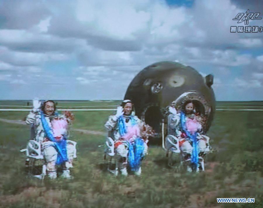 The screen at the Beijing Aerospace Control Center shows astronauts Zhang Xiaoguang, Nie Haisheng and Wang Yaping (from left to right) waving to people after going out of the re-entry capsule of China's Shenzhou-10 spacecraft following its successful landing at the main landing site in north China's Inner Mongolia Autonomous Region on June 26, 2013. (Xinhua/Wang Yongzhuo)