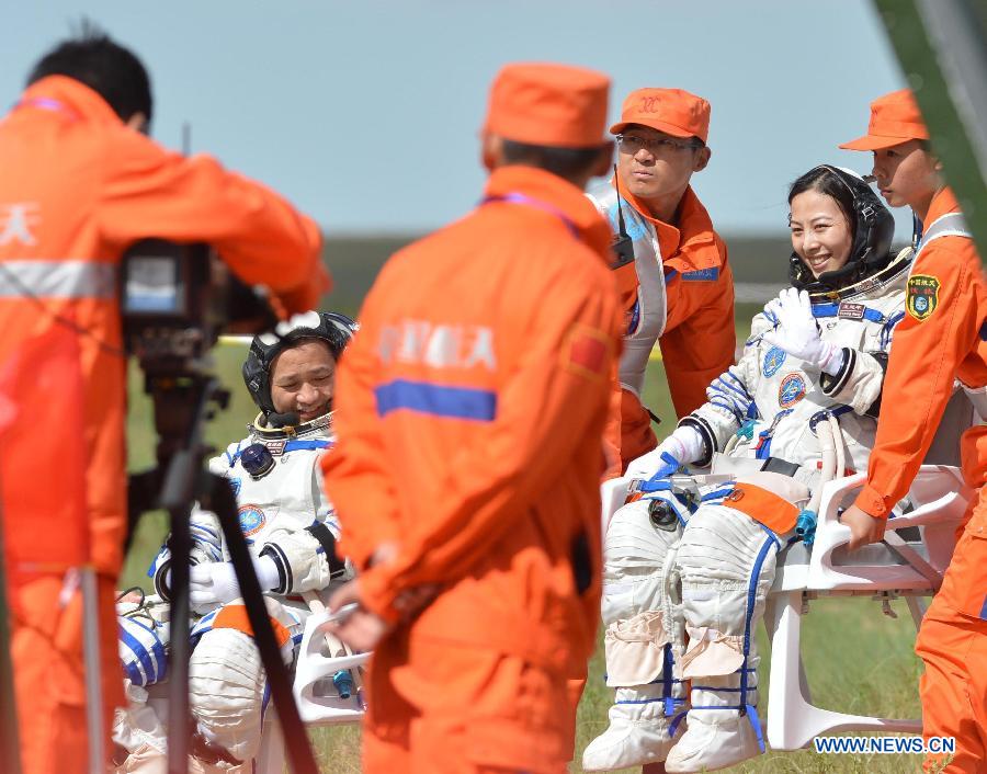 Female astronaut Wang Yaping (R) waves after getting out of the re-entry capsule of China's Shenzhou-10 spacecraft following its landing in north China's Inner Mongolia Autonomous Region on June 26, 2013. Commander-in-chief of China's manned space program Zhang Youxia has announced that the Shenzhou-10 mission was successful after the three crewmembers landed safely and left the spacecraft's re-entry module Wednesday morning. (Xinhua/Ren Junchuan)
