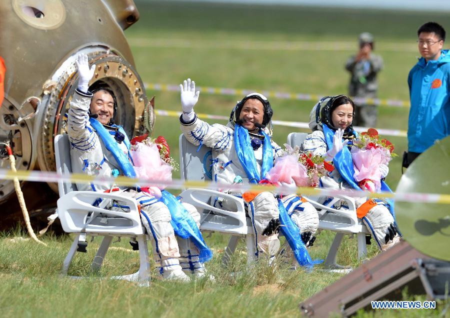 Astronauts Zhang Xiaoguang, Nie Haisheng and Wang Yaping (from left to right) wave after getting out of the re-entry capsule of China's Shenzhou-10 spacecraft following its successful landing at the main landing site in north China's Inner Mongolia Autonomous Region on June 26, 2013. (Xinhua/Zhang Ling)