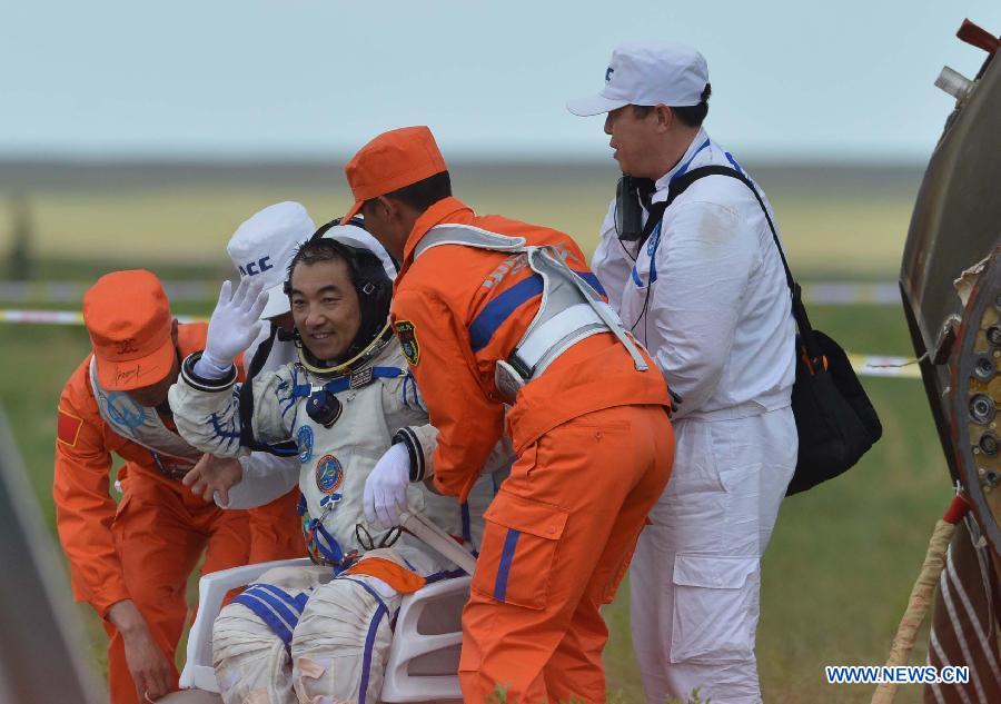 Astronaut Zhang Xiaoguang waves after going out of the re-entry capsule of China's Shenzhou-10 spacecraft following its successful landing at the main landing site in north China's Inner Mongolia Autonomous Region on June 26, 2013. (Xinhua/Ren Junchuan) 