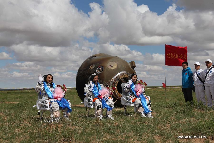 Astronauts Zhang Xiaoguang, Nie Haisheng and Wang Yaping (from left to right) wave to people after going out of the re-entry capsule of China's Shenzhou-10 spacecraft following its successful landing at the main landing site in north China's Inner Mongolia Autonomous Region on June 26, 2013. (Xinhua/Wang Jianmin)