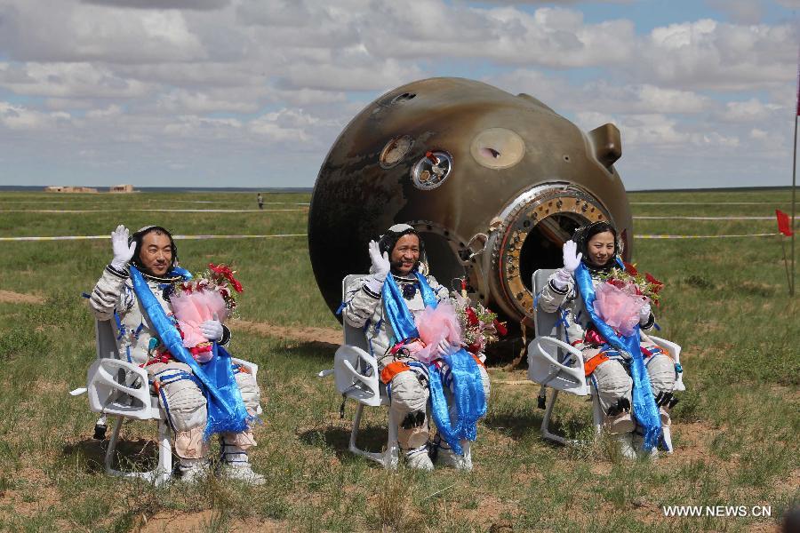 Astronauts Zhang Xiaoguang, Nie Haisheng and Wang Yaping (from left to right) wave to people after going out of the re-entry capsule of China's Shenzhou-10 spacecraft following its successful landing at the main landing site in north China's Inner Mongolia Autonomous Region on June 26, 2013. (Xinhua/Wang Jianmin)