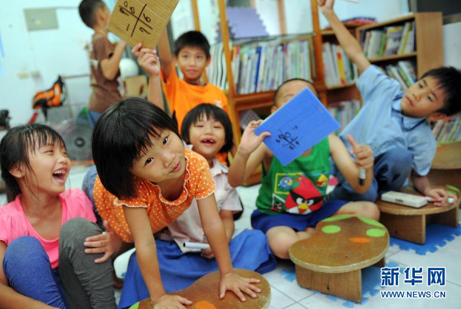 Children answer the teacher's question in the activity center on June 20, 2013. (Photo/Xinhua)