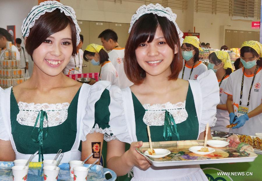 Two working staff members send food to visitors at Food Taipei 2013 exhibition in Taipei, southeast China's Taiwan, June 26, 2013. The four-day Food Taipei 2013 show kicked off Wednesday at Taipei World Trade Center Nangang Exhibition Hall. (Xinhua/Tao Ming)