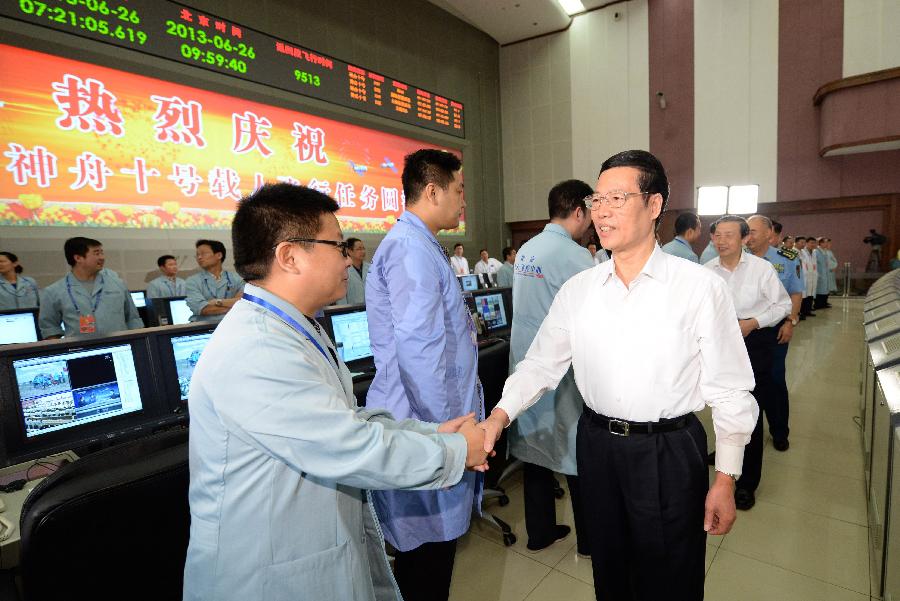 Chinese Vice Premier Zhang Gaoli (R, front) shakes hands with staff workers at the Beijing Aerospace Control Center in Beijing, capital of China, June 26, 2013. Zhang watched the live broadcast of the return and recovery of Shenzhou-10 spacecraft Wednesday morning and read a congratulatory letter on behalf of the Central Committee of the Communist Party of China, the State Council and the Central Military Commission. (Xinhua/Ma Zhancheng) 