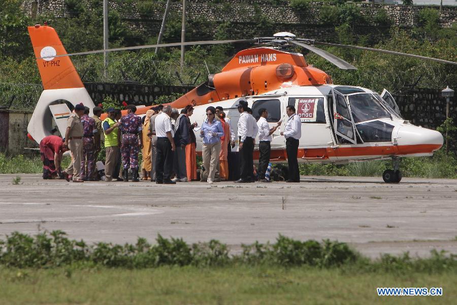 Rescuers work next to a helicopter at the airport in Dehradun, northern Indian state of Uttarakhand, June 26, 2013. There are still an estimated 7000 people stranded in the flood while authorities use military planes and helicopters in the rescue in flood-ravaged northern India. (Xinhua/Zheng Huansong) 
