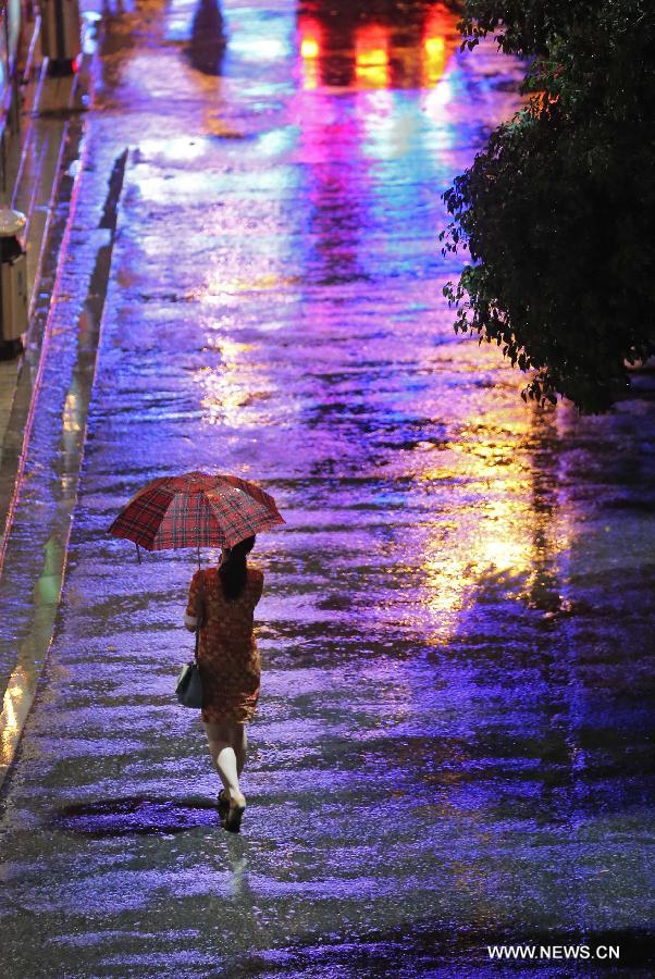A woman walks in the rain in Changsha, capital of central China's Hunan Province, June 26, 2013. The city was hit by rain on Wednesday evening. (Xinhua/Li Ga) 