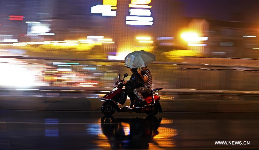 Two people travel in the rain in Changsha, capital of central China's Hunan Province, June 26, 2013. The city was hit by rain on Wednesday evening. (Xinhua/Li Ga) 
