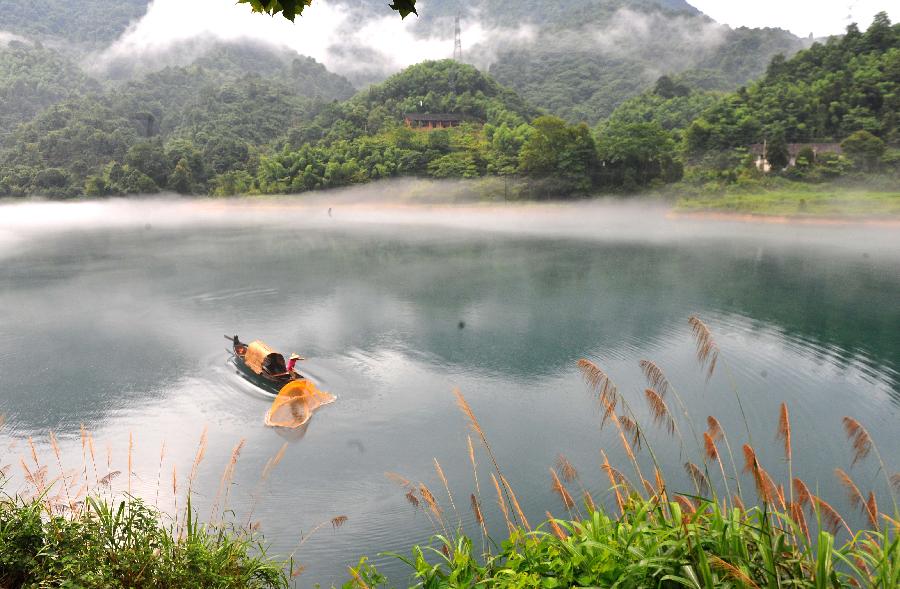 A fisherman casts a net on the fog-enveloped Xiaodongjiang River in Zixing City of central China's Hunan Province, June 26, 2013. (Xinhua/Chen Haining)