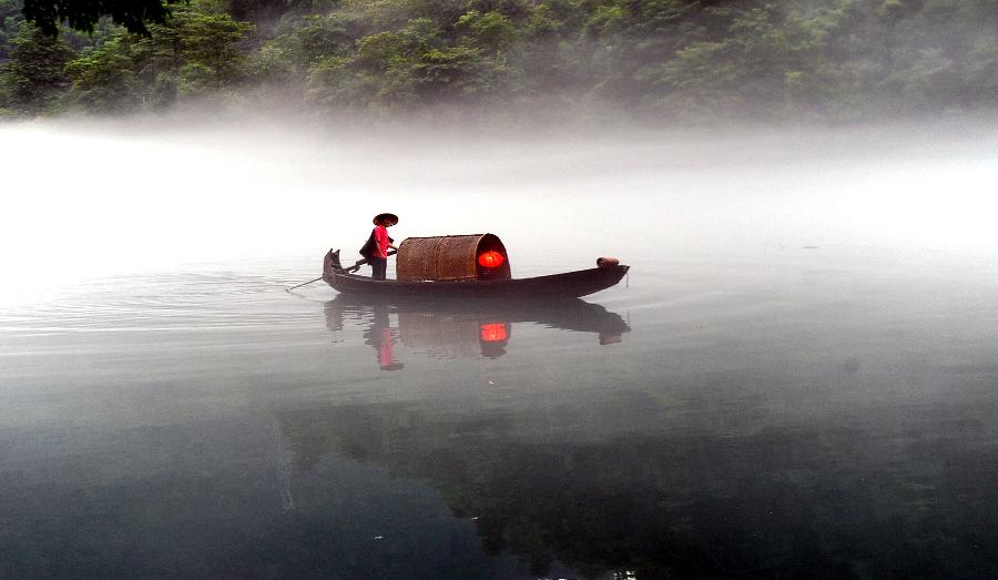 A fisherman paddles a boat on the fog-enveloped Xiaodongjiang River in Zixing City of central China's Hunan Province, June 25, 2013. (Xinhua/Chen Haining)