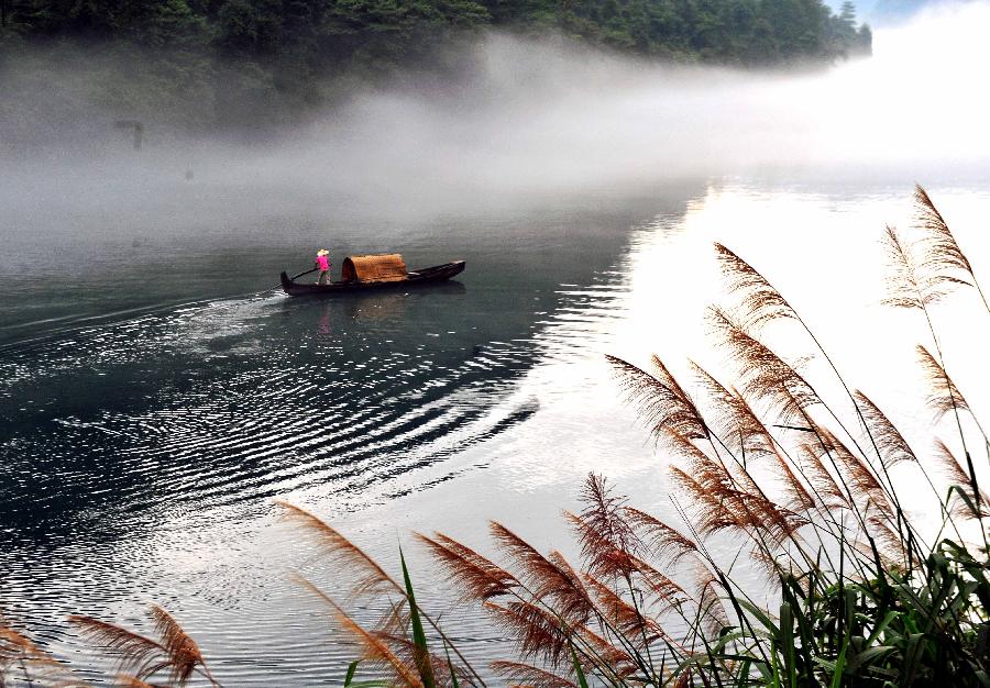 A fisherman paddles a boat on the fog-enveloped Xiaodongjiang River in Zixing City of central China's Hunan Province, June 26, 2013. (Xinhua/Chen Haining)