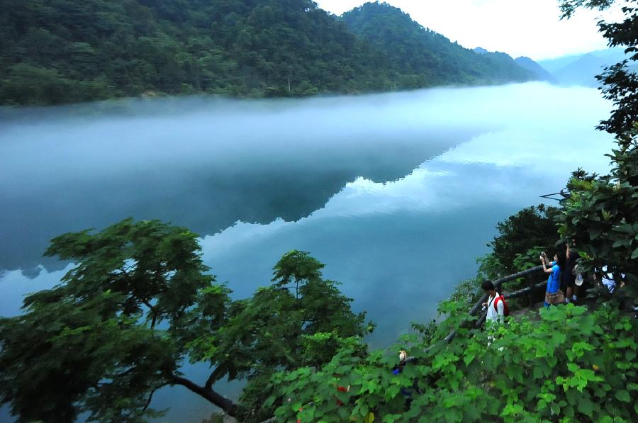 Tourists visit the fog-enveloped Xiaodongjiang River in Zixing City of central China's Hunan Province, June 25, 2013. (Xinhua/Chen Haining)