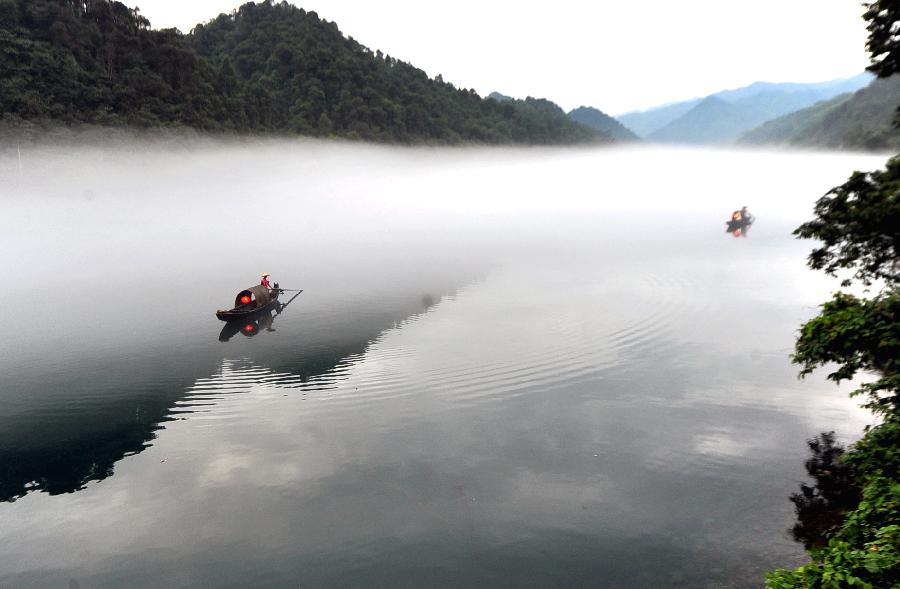 A fisherman paddles a boat on the fog-enveloped Xiaodongjiang River in Zixing City of central China's Hunan Province, June 25, 2013. (Xinhua/Chen Haining) 