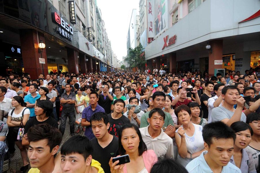 People gather outside a burning building in Nanning, south China’s Guangxi on July 7, 2012. The fire broke out at a building on a commercial street on that day. (Photo/CNTV)