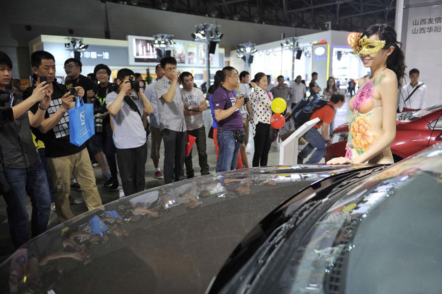 An auto model with body painting at an auto show attracts visitors in Taiyuan, north China’s Shanxi province on May 16, 2013. (Photo/CNTV) 