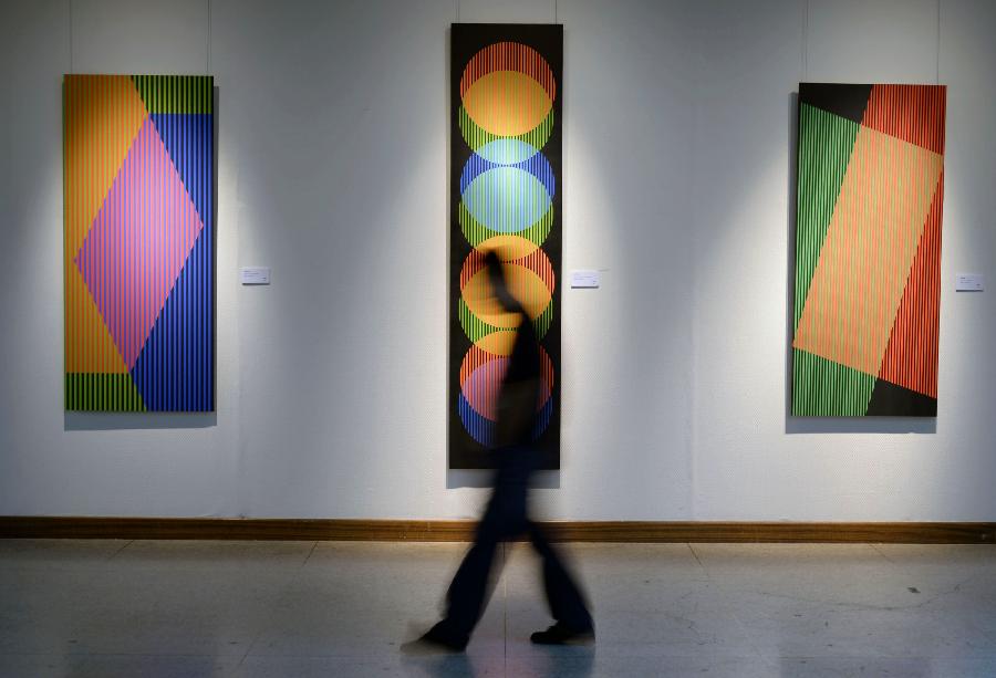 A visitor walks past artworks during the exhibition of the Venezuelan artist Carlos Cruz-Diez "Circumstance and Ambiguity of Color" in Hangzhou, capital of east China's Zhejiang Province, June 27, 2013. The exhibition will last till July 23. (Xinhua/Shi Jianxue)  