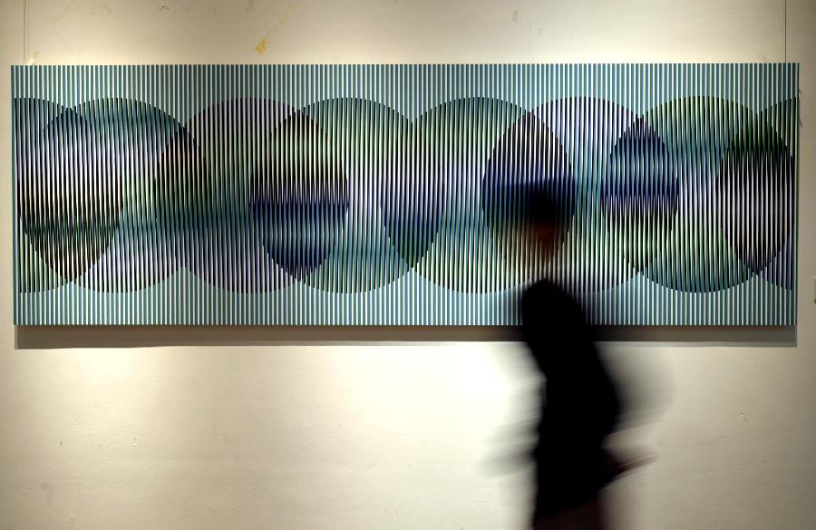 A visitor walks past artworks during the exhibition of the Venezuelan artist Carlos Cruz-Diez "Circumstance and Ambiguity of Color" in Hangzhou, capital of east China's Zhejiang Province, June 27, 2013. The exhibition will last till July 23. (Xinhua/Shi Jianxue) 