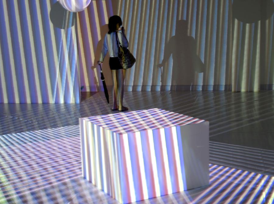 A visitor takes photo of artworks during the exhibition of the Venezuelan artist Carlos Cruz-Diez "Circumstance and Ambiguity of Color" in Hangzhou, capital of east China's Zhejiang Province, June 27, 2013. The exhibition will last till July 23. (Xinhua/Shi Jianxue)  