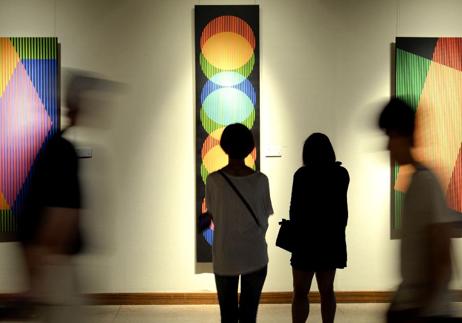 Visitors look at artworks during the exhibition of the Venezuelan artist Carlos Cruz-Diez "Circumstance and Ambiguity of Color" in Hangzhou, capital of east China's Zhejiang Province, June 27, 2013. The exhibition will last till July 23. (Xinhua/Shi Jianxue) 
