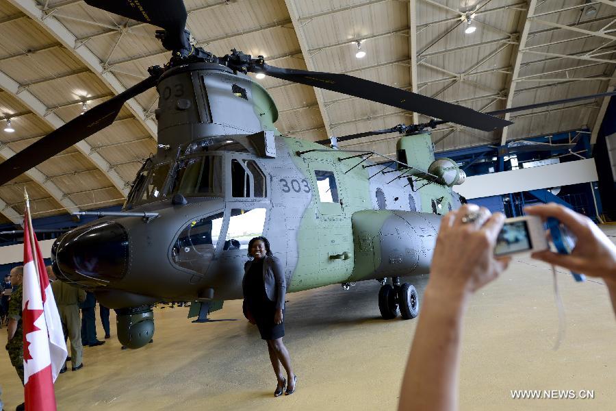 A woman poses beside a new CH-147F Chinook helicopter during the unveiling ceremony in Ottawa June 27, 2013. The 15 newly purchased F-model Chinooks will be engaged in support, domestic and foreign operations for the Royal Canadian Air Force's reactivated "450 Tactical Helicopter Squadron" based in Petawawa, Ontario. (Xinhua/James Park)