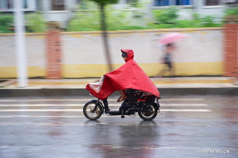 A woman rides electric bicycle in rain in Nanchang, capital of east China's Jiangxi Province, June 28, 2013. Heavy rainfall hit parts of the province on Friday. (Xinhua/Hu Chenhuan) 