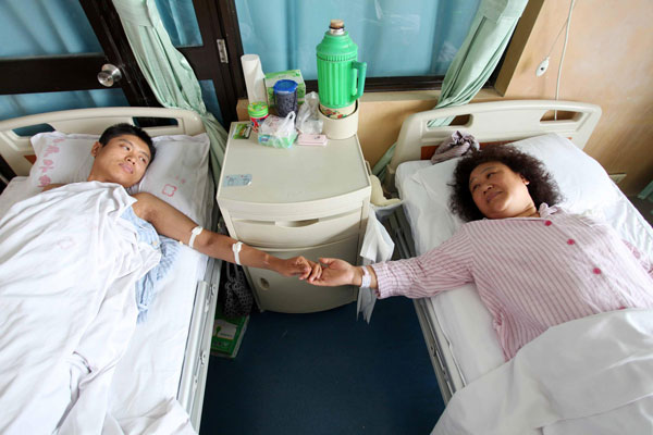 Wang Chuanli and her son hold hands before the kidney transplant operation, June 27, 2013. [Photo/Xinhua]