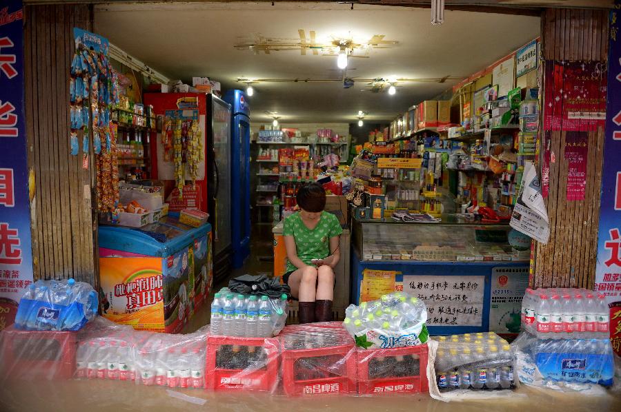 A merchant piles up bottled drinks to build a "dam" to prevent the flood in Nanchang, capital of east China's Jiangxi Province, June 28, 2013. Heavy rainfall hit the city on Friday. (Xinhua/Zhou Mi)