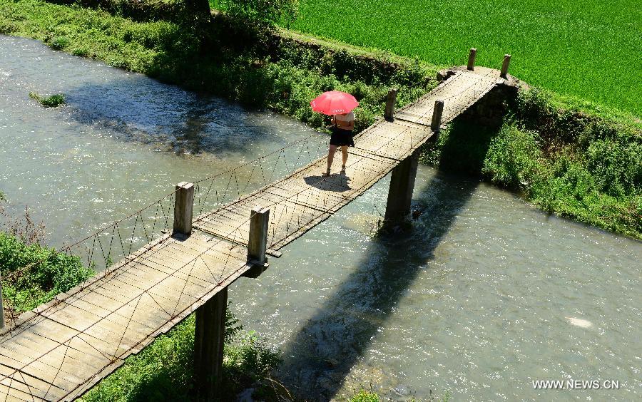 An village walks through a bridge at Jinlongba Village in Enshi City, central China's Hubei Province, June 27, 2013. The Jinlongba Village was listed among the 646 Chinese Traditional Villages in 2012 and villagers here followed the traditional way of living. (Xinhua/Yang Shunpi)  